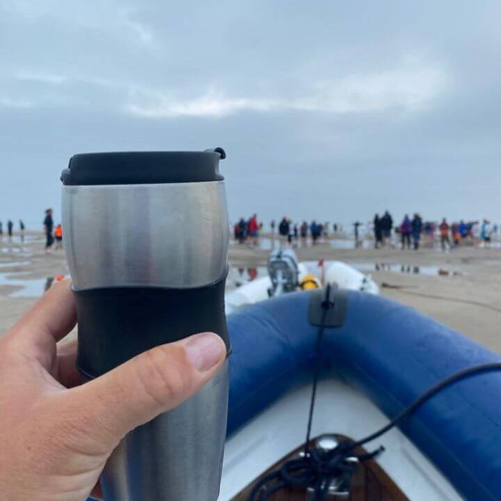 Nic holding a travel cup of tea onboard Bluetooth RIB at Bramble Bank Cricket Match
